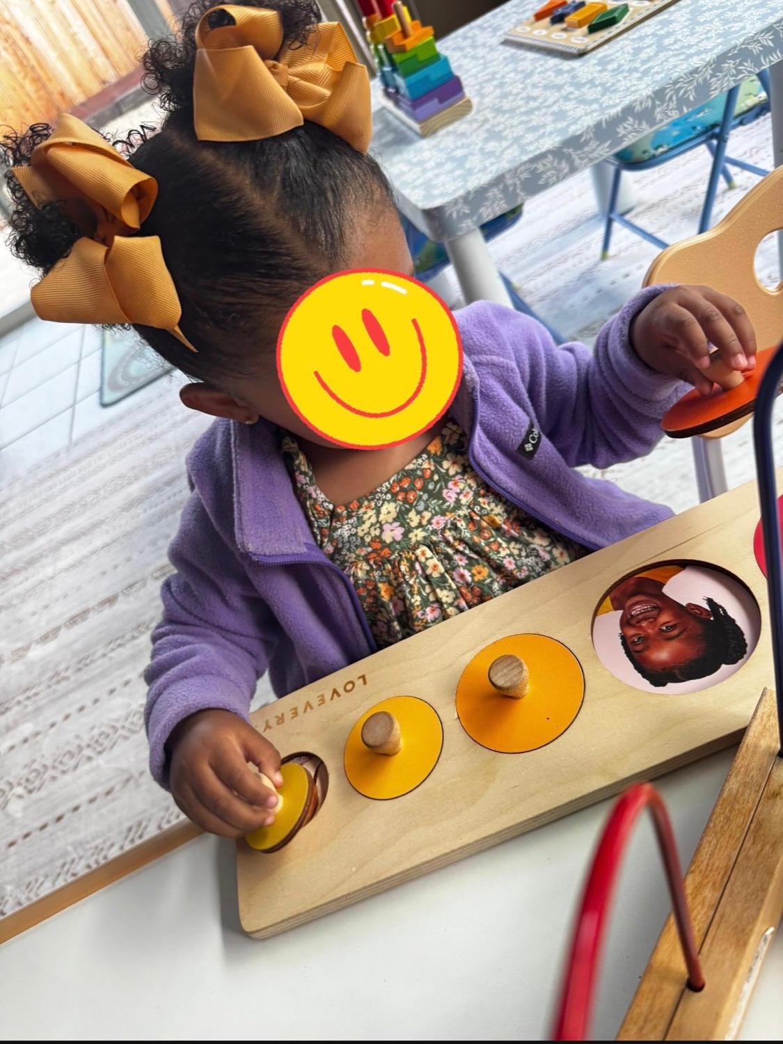 Child using a wooden learning activity board with face covered for privacy