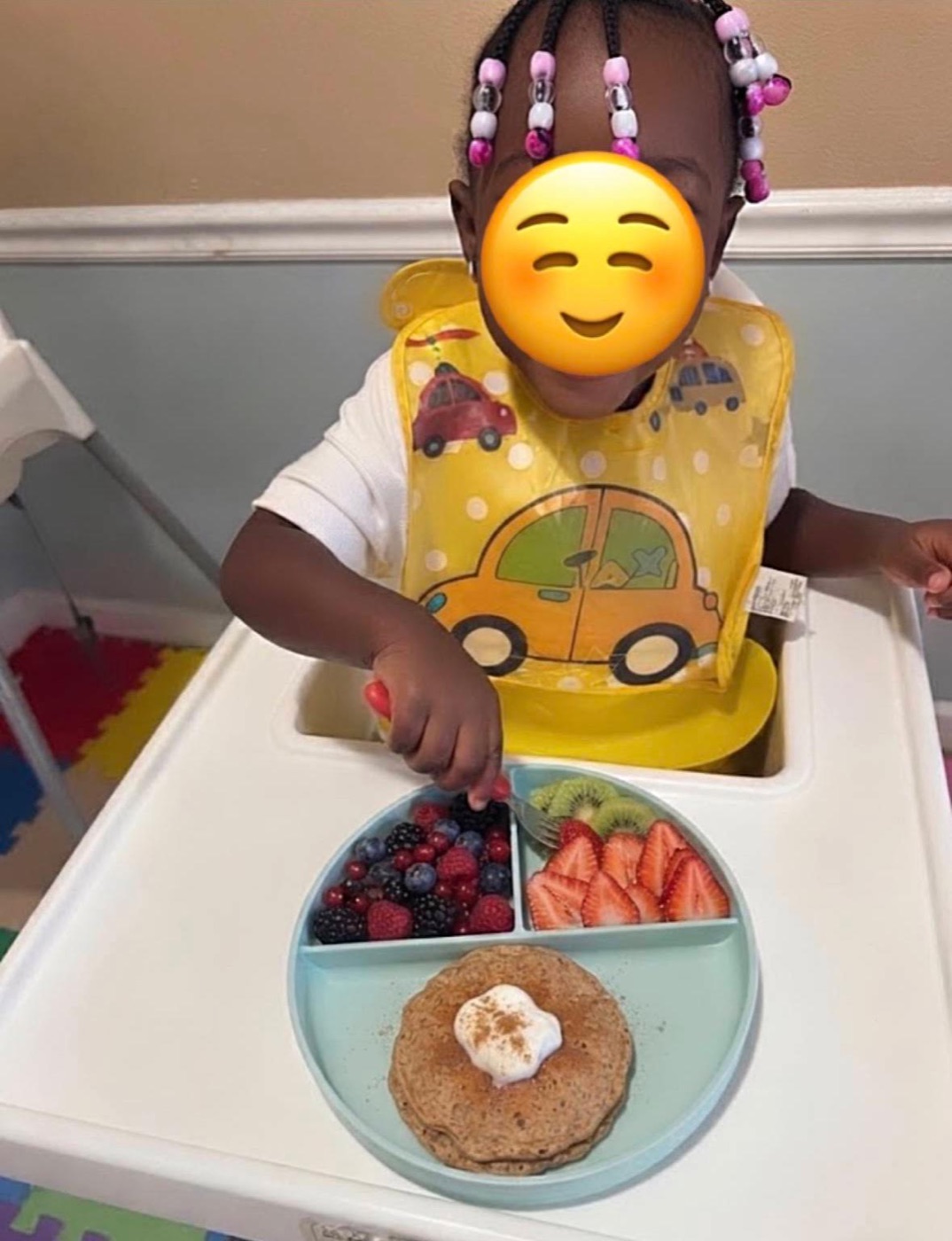 Child enjoying a healthy breakfast with pancakes and fresh fruit at Ale's Home Childcare with face covered for privacy