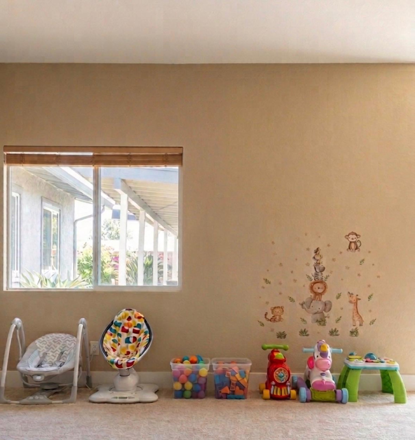 Infant play corner with swings, sensory bins, ride-on toys, and wall decals
