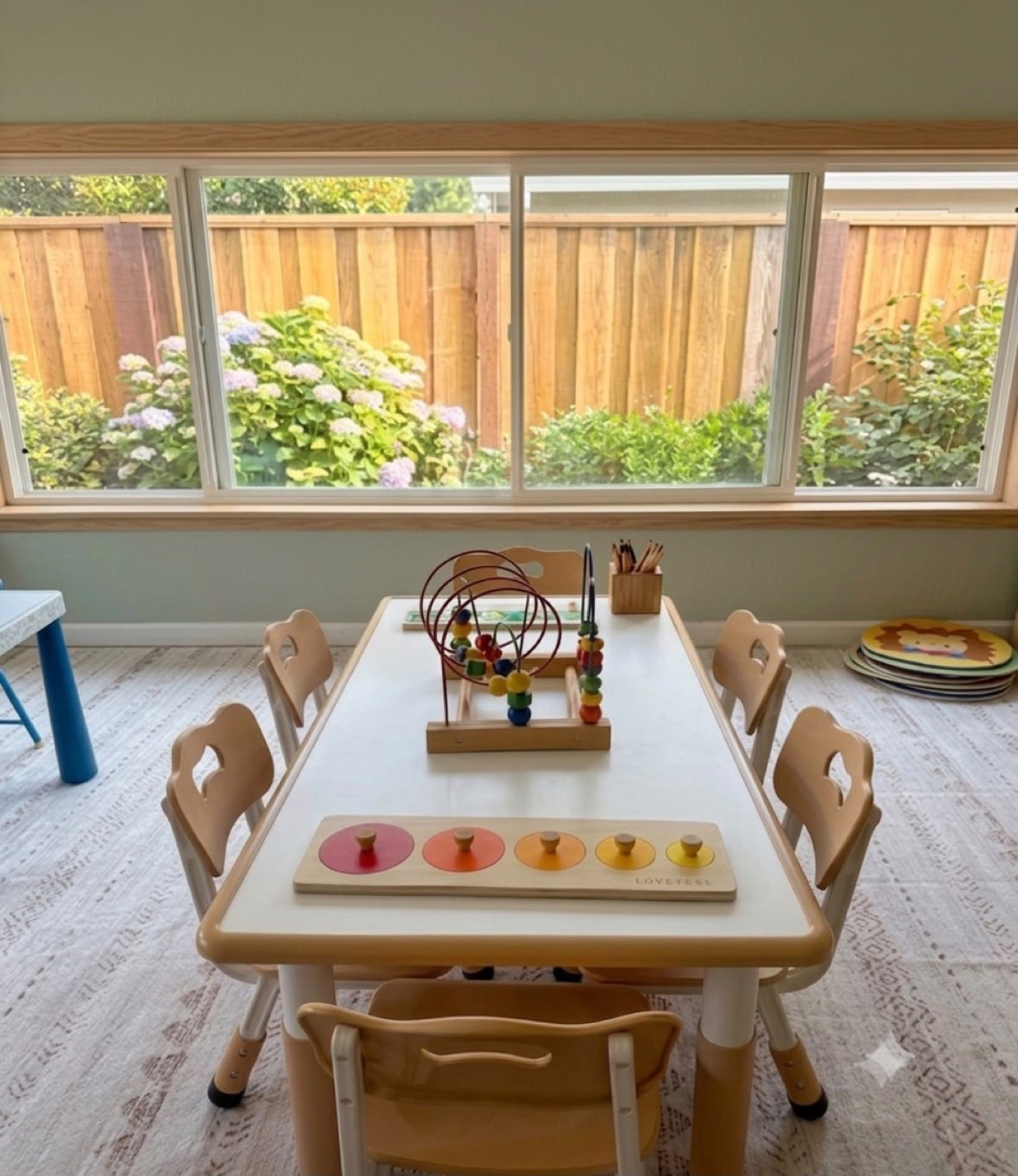 Child-sized learning table with wooden activities near a sunny garden window