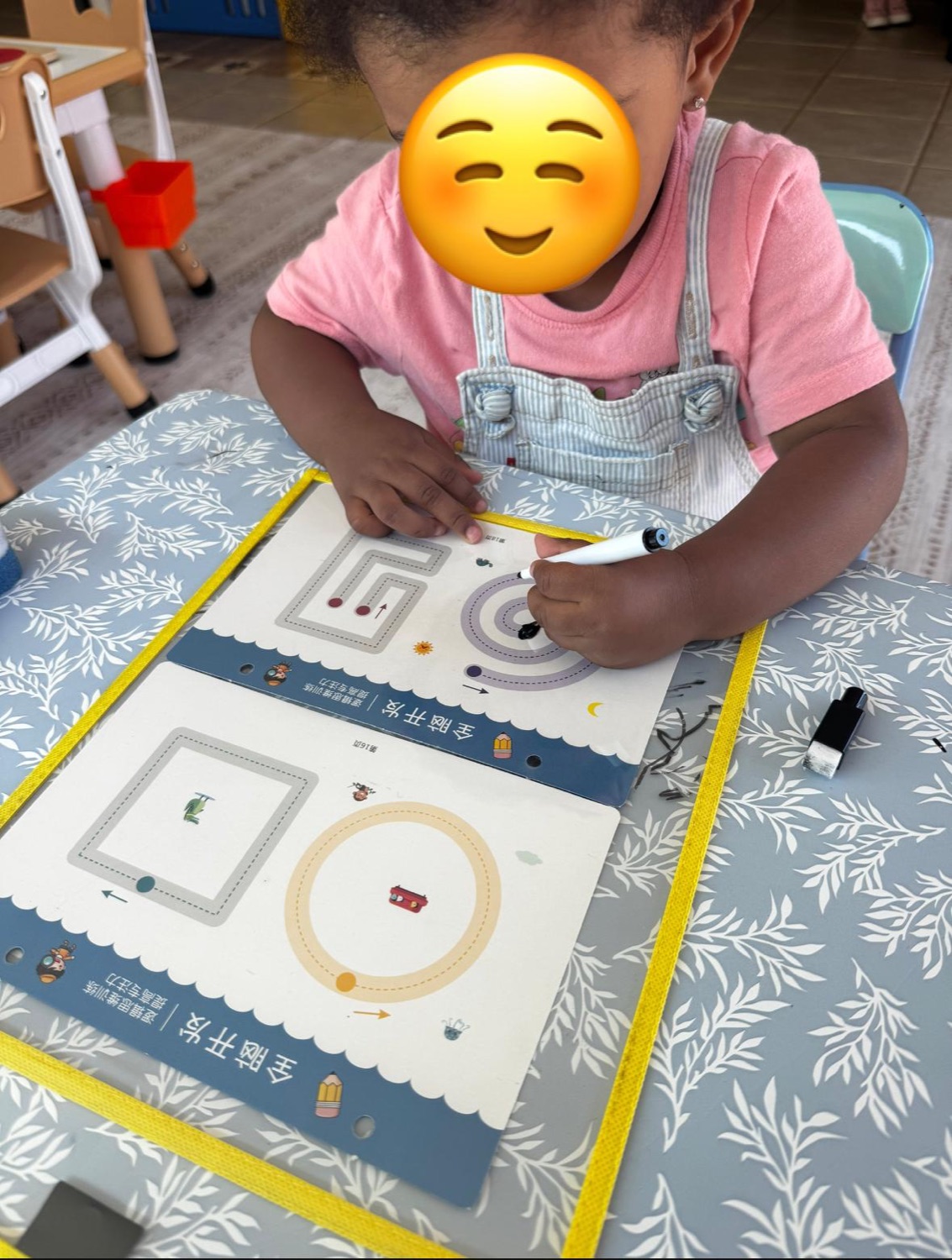 Child practicing shape tracing with a marker at the learning table with face covered for privacy