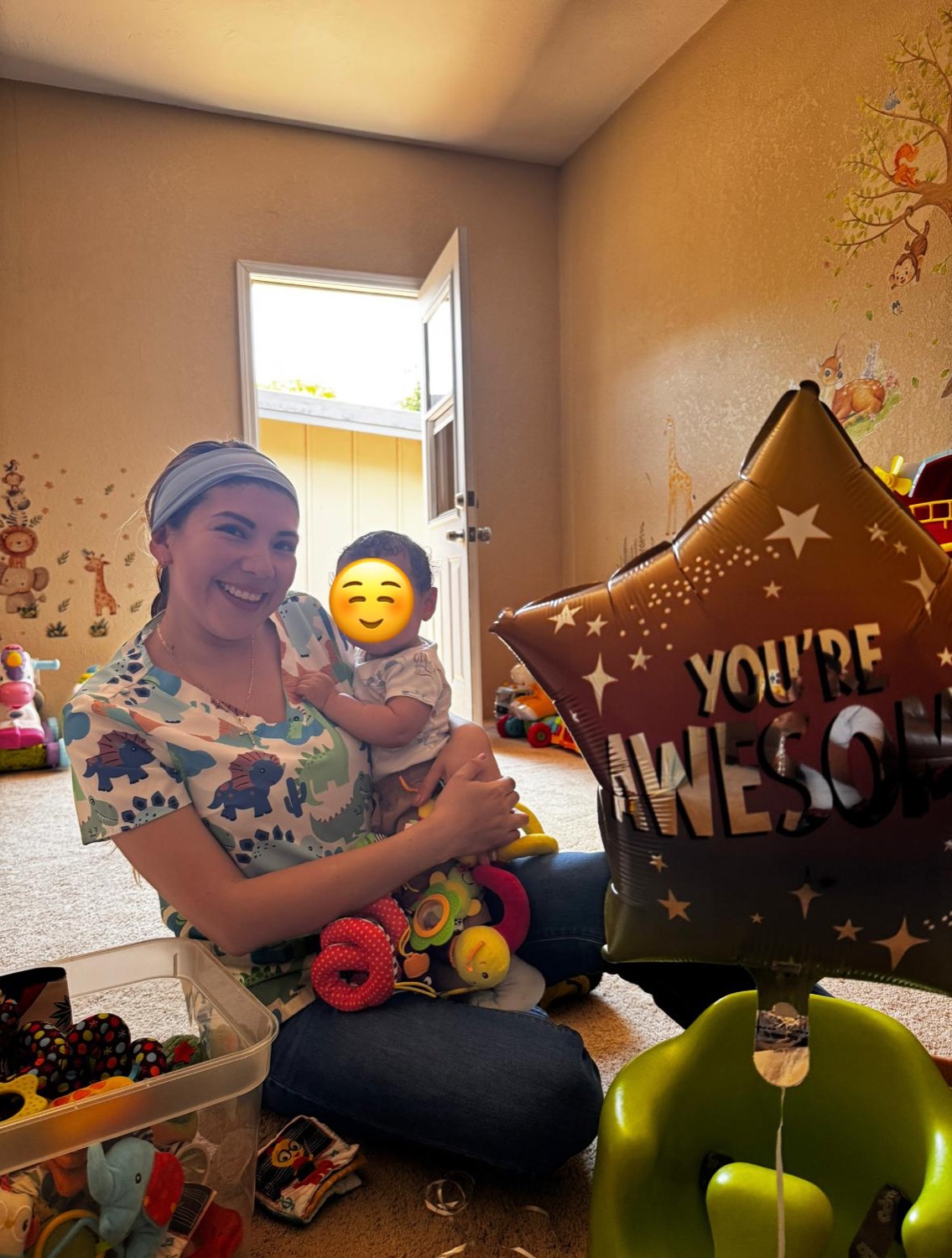 Ale smiling while holding a child with the child's face covered for privacy